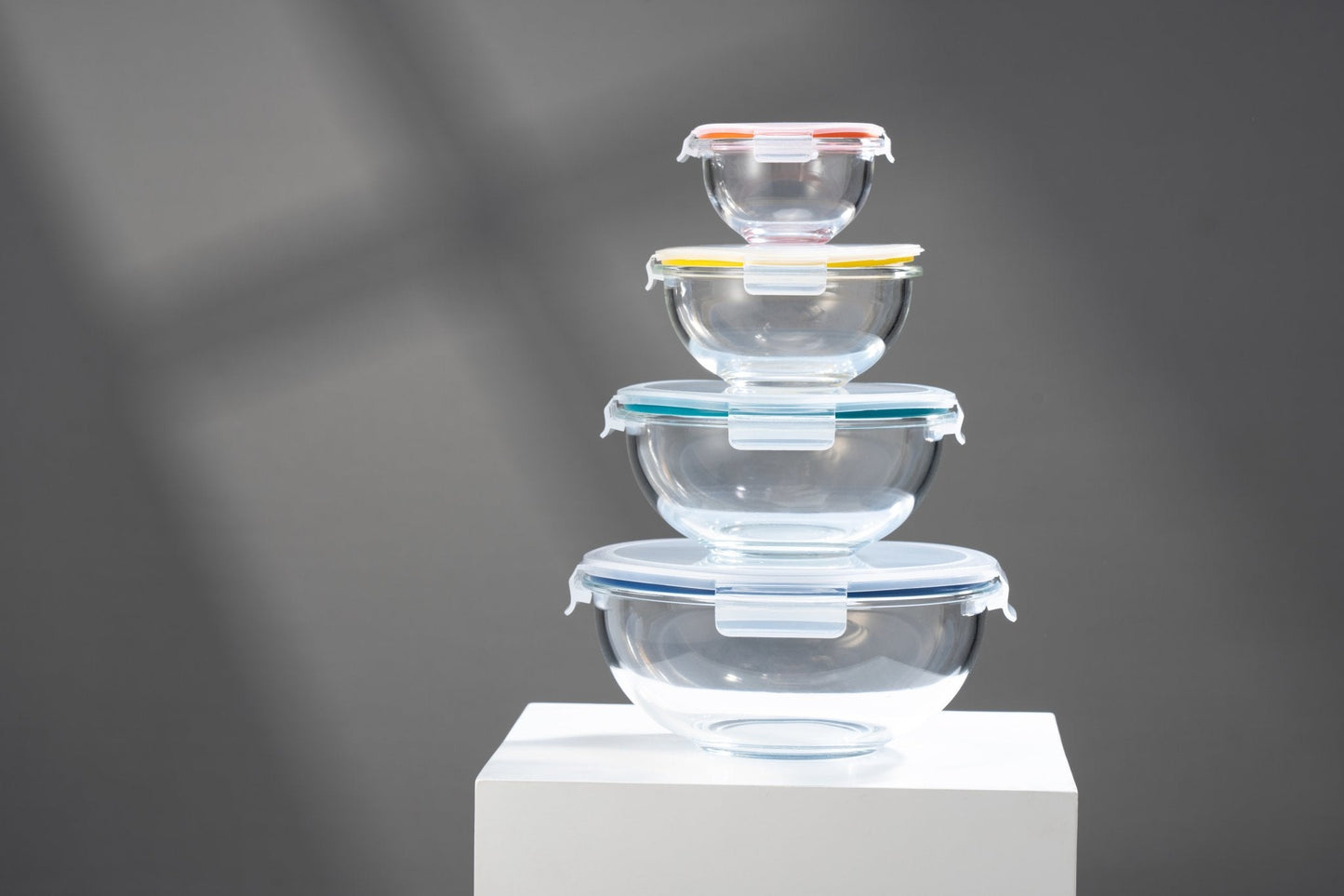 Stack of clear glass food containers on a white platform with a dark background