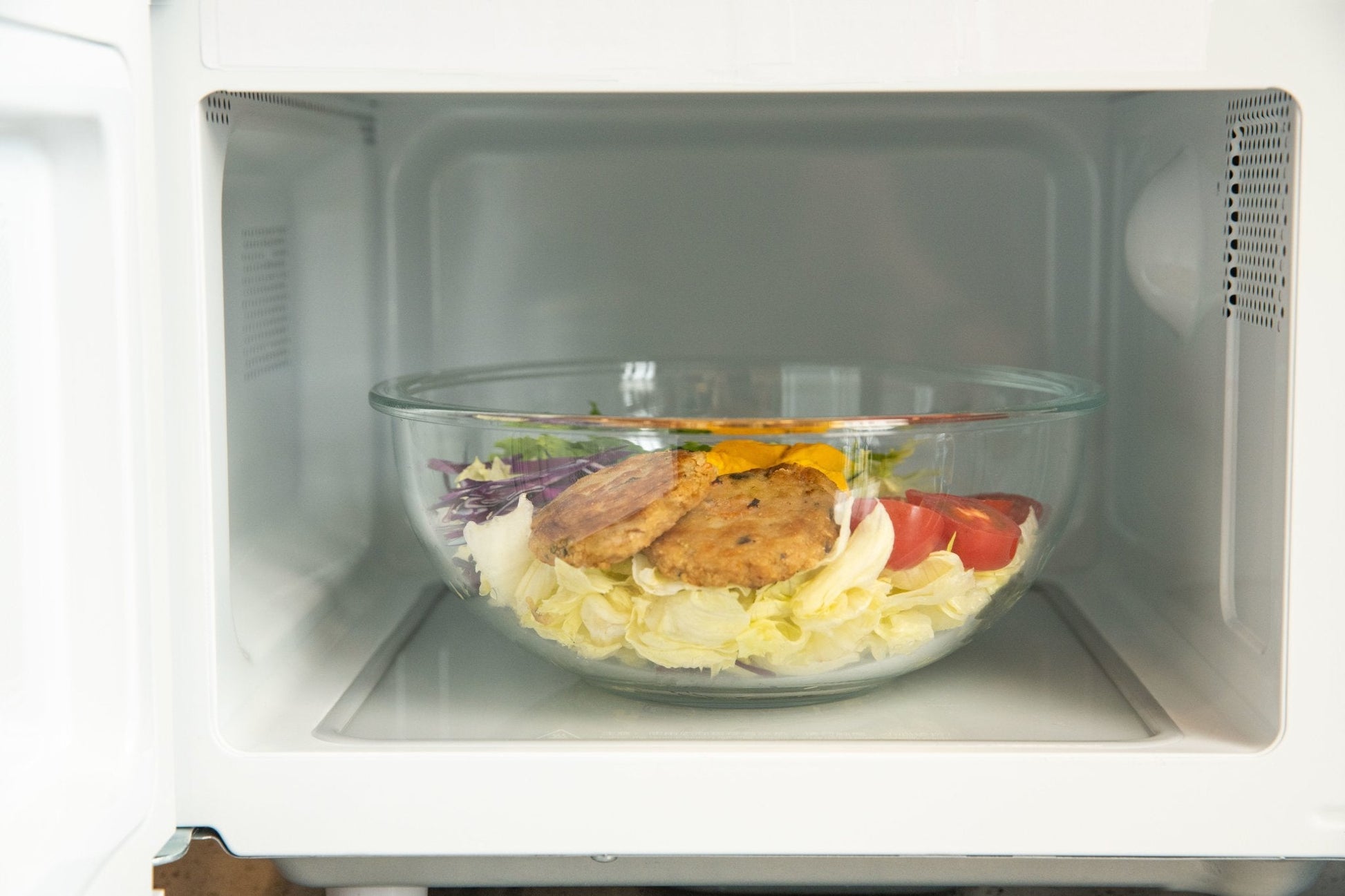 Glass bowl with salad inside a microwave oven