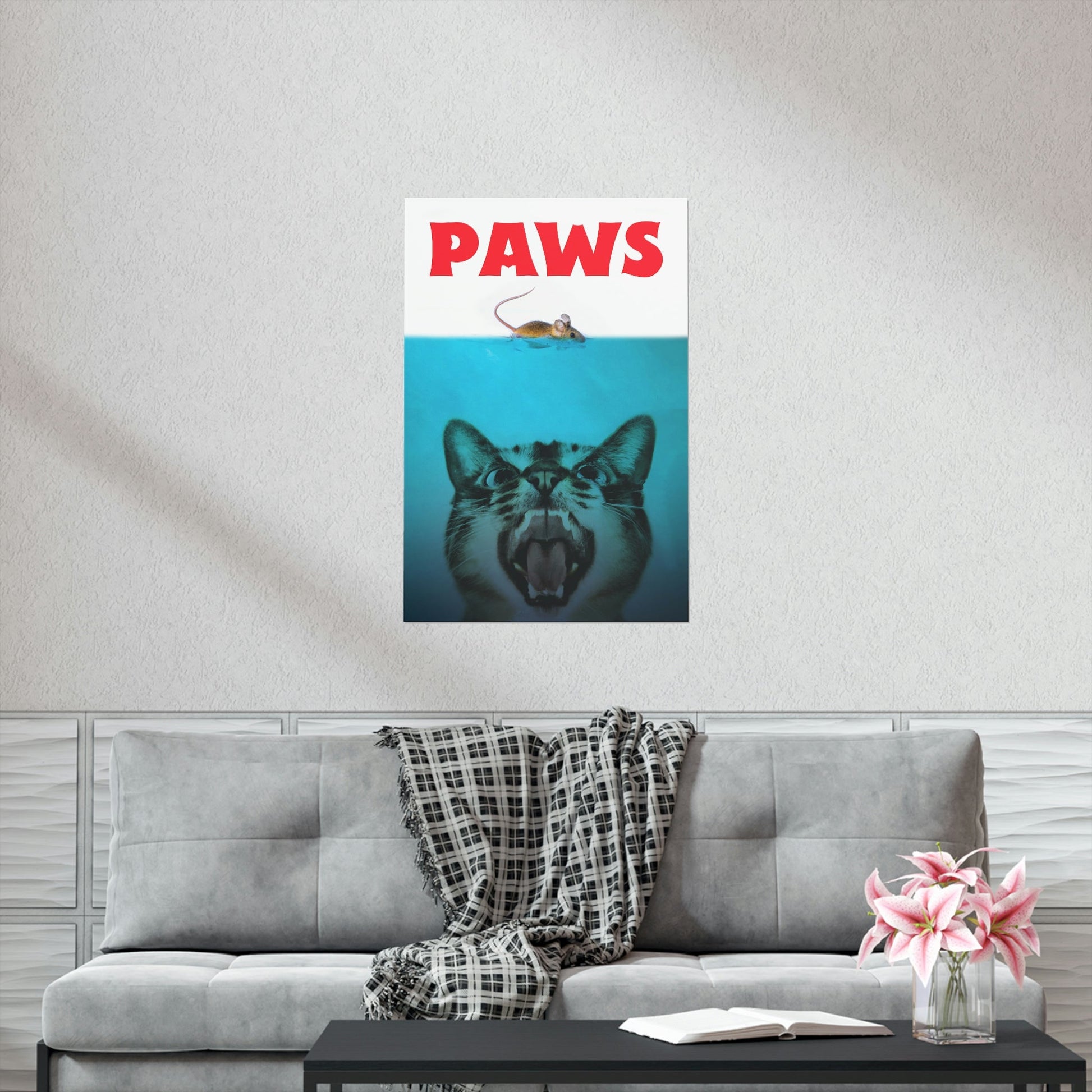 Poster with a cat's face and 'PAWS' text on a wall above a gray sofa.