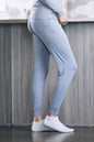 Person wearing light blue leggings and white socks standing against a wooden panel background