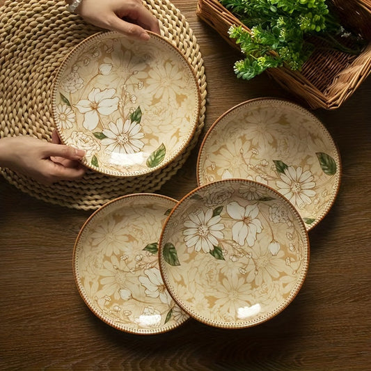 Two round ceramic plates with a floral design, displayed on a wooden table with a person's hands partially visible, holding one of the plates.
