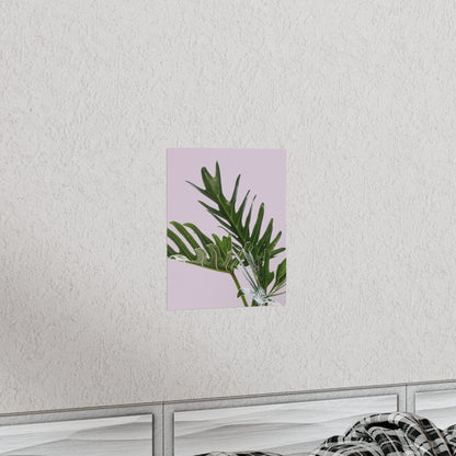 Framed artwork with green leaves on a pink background, mounted on a white wall.