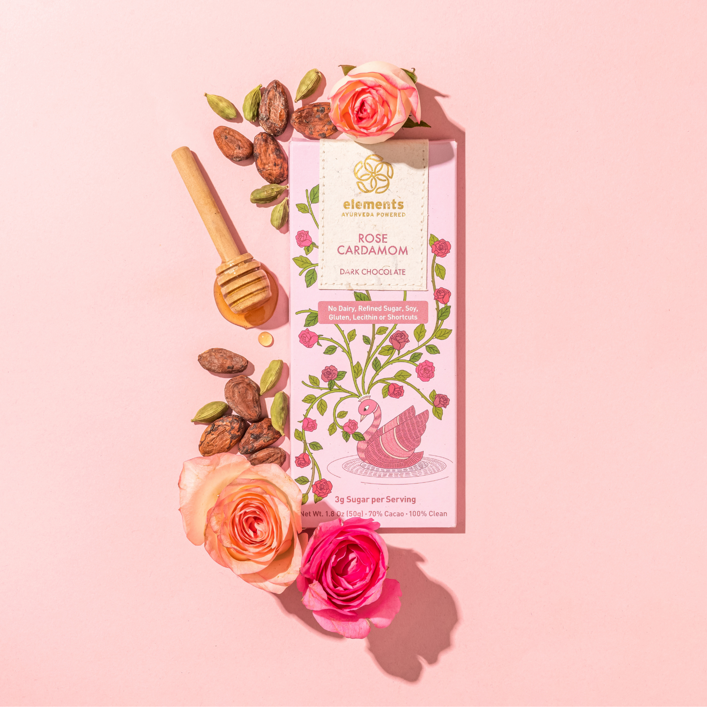 Chocolate bar packaging with roses, cardamom, and honey on a pink background