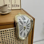 Vintage-style clock on a wooden surface with a cup and saucer in the background.
