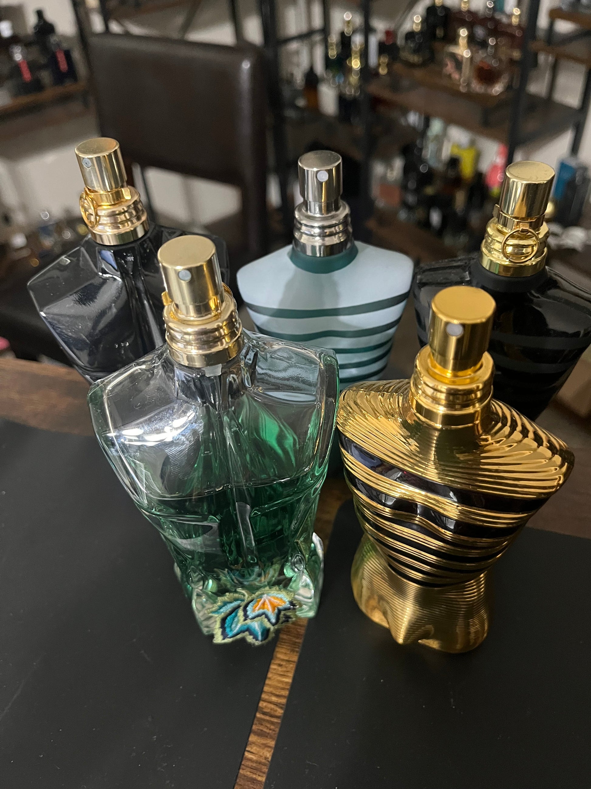 Collection of perfume bottles with gold and silver caps on a dark surface.