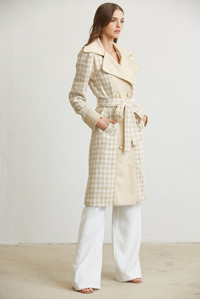 Woman wearing a long beige coat with a belt against a white background