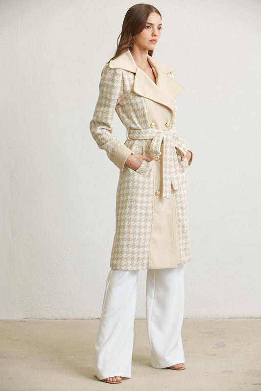Woman wearing a long beige coat with a belt against a white background