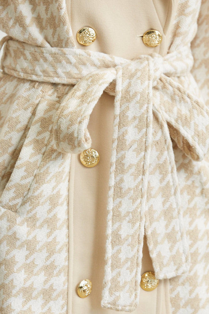 Close-up of a patterned coat with gold buttons and a tie waist.