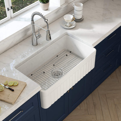 White kitchen sink with blue cabinets and a window in the background