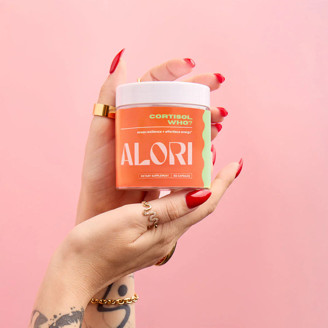 Hand holding a supplement container labeled 'ALORI' against a pink background