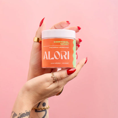 Hand holding a supplement container labeled 'ALORI' against a pink background