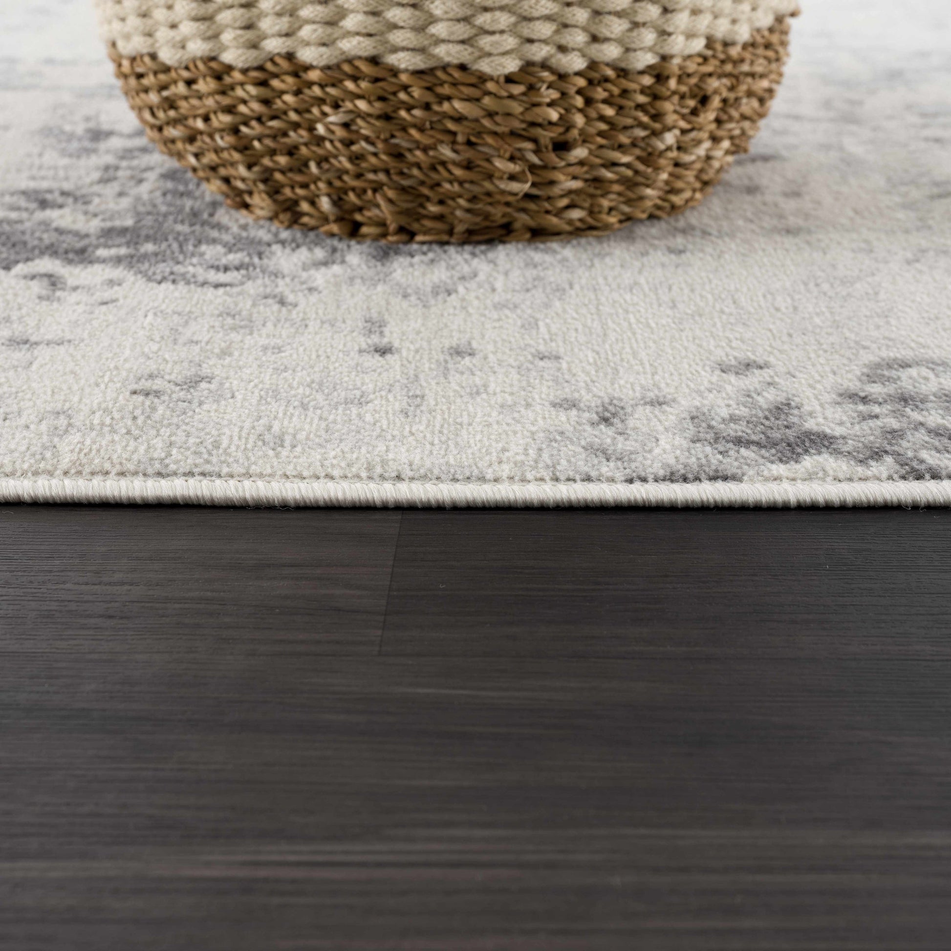 Close-up of a textured rug with a woven basket on a wooden floor.