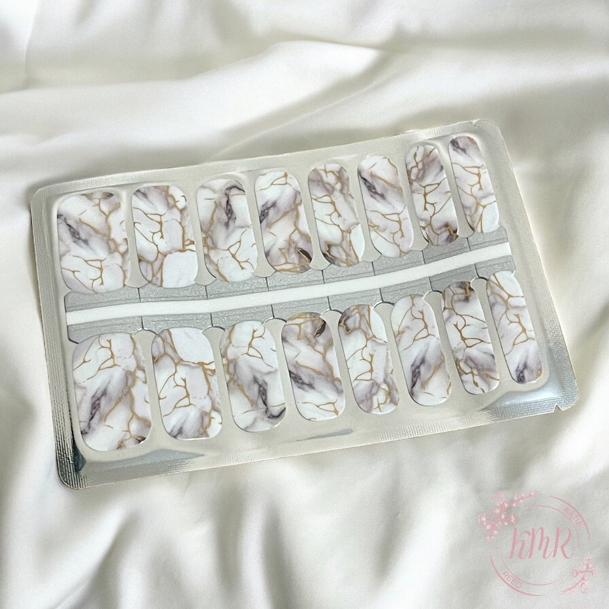 Marble-patterned nail art stickers in a clear plastic case on a white fabric background