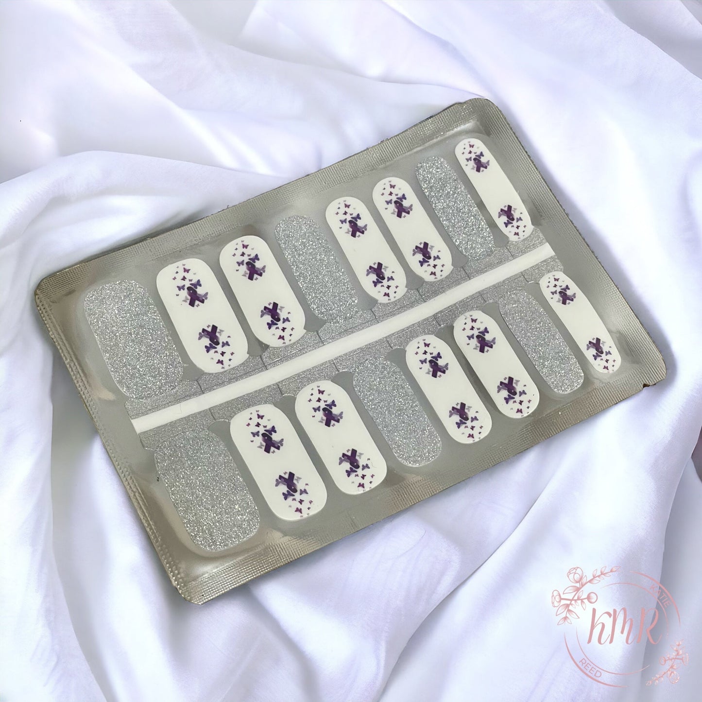 Nail art stickers with silver and white design on a white fabric background