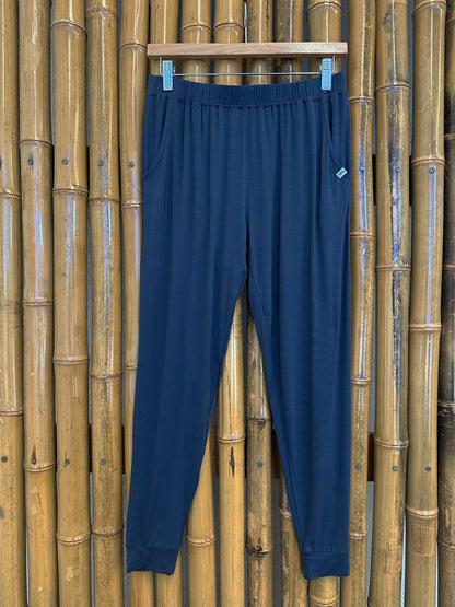 Navy blue pants hanging on a wooden rack against a bamboo wall