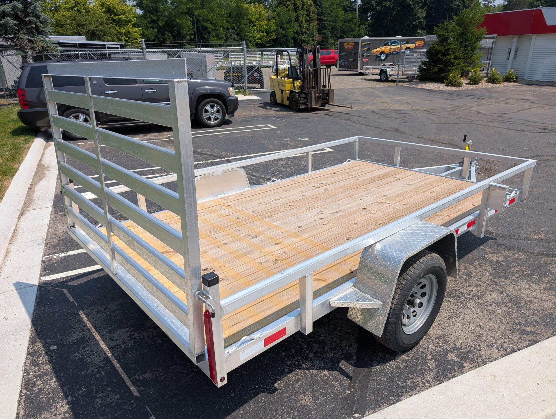 Metal utility trailer with wooden floor in a parking lot