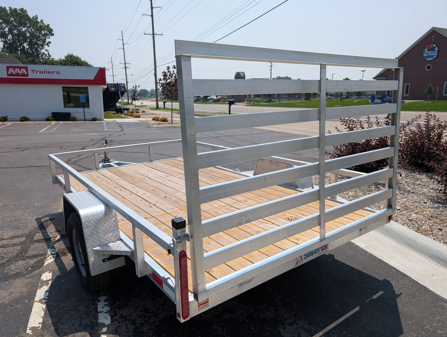Metal utility trailer with wooden floor in a parking lot
