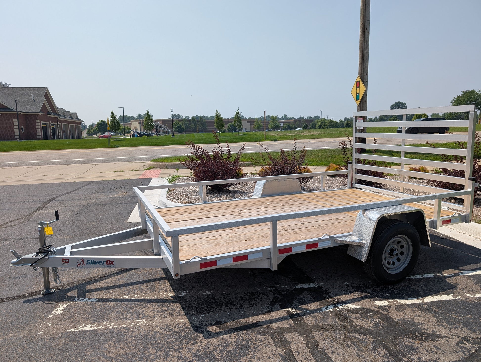 White utility trailer with wooden floor on a paved road