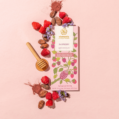 Raspberry dark chocolate bar with raspberries, cocoa beans, and a honey dipper on a pink background