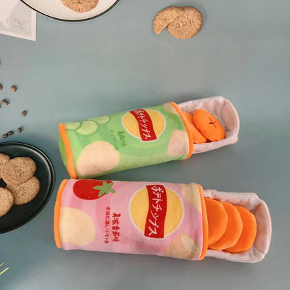 Two plush toy cans resembling snack packages on a gray surface with cookies around.