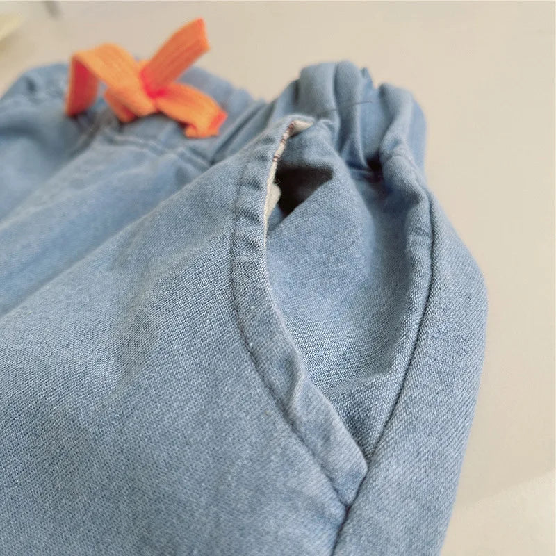 Close-up of a blue denim fabric with a small orange object on a beige background