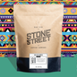 Kraft paper coffee bag with 'Stone Street Coffee Company' branding on a colorful geometric patterned background.