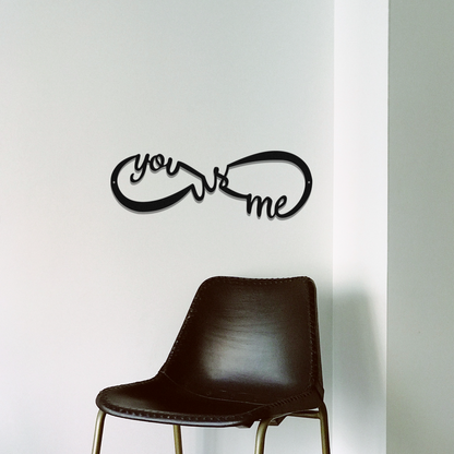 Decorative wall art with 'you love me' text on a white wall with a brown chair.