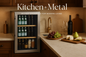 A sophisticated marketing image showing a stainless steel beverage refrigerator in a warm, inviting kitchen setting. The refrigerator is styled with beverages and elegant food items on a marble countertop. The Kitchen + Metal logo appears in an elegant contemporary font with the tagline "Refined Essentials for Modern Living". The image beautifully balances cool metallics with warm wood tones and copper accents, creating a sophisticated yet welcoming atmosphere that embodies both elements of the brand name.
