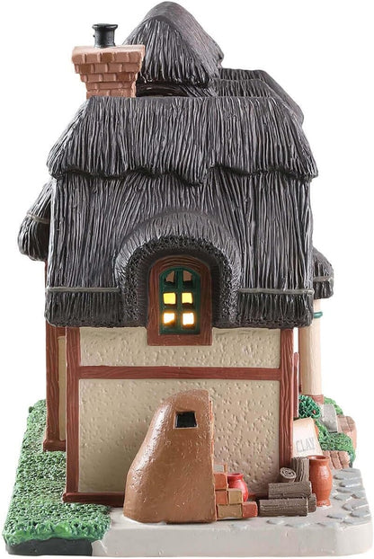 Decorative model of a thatched-roof cottage with a light inside the window on a white background.