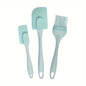 A set of three silicone kitchen utensils, including a spatula, a brush, and a scraper, in a light blue color, displayed on a two-tone background with orange and blue sections.