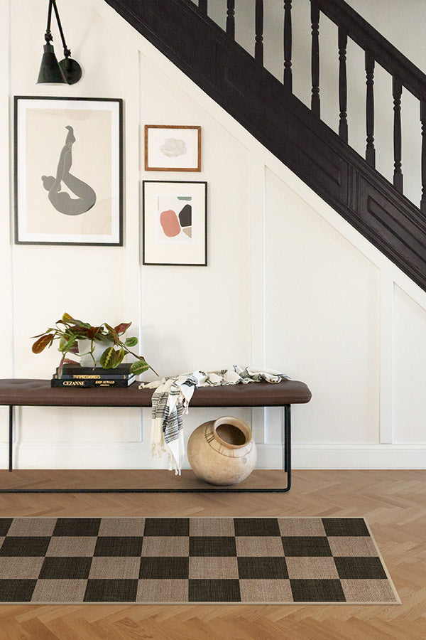 Nook with a wooden bench, plant, and decorative items against a staircase.