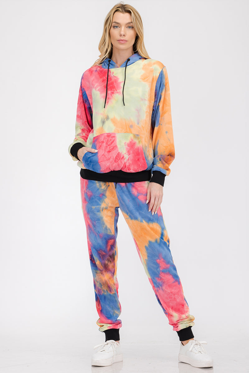Person wearing a colorful tie-dye hoodie and pants set on a white background