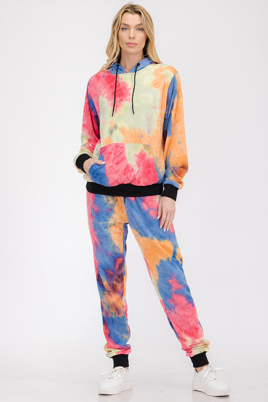 Person wearing a colorful tie-dye hoodie and pants set on a white background
