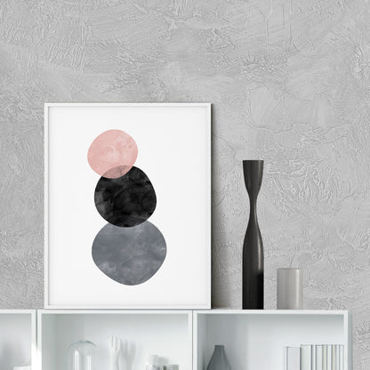 Framed abstract art print with pink, black, and gray circles on a textured wall.