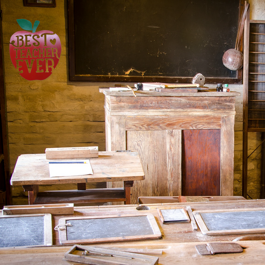 Vintage classroom setup with wooden desks and a blackboard, featuring a 'Best Teacher Ever' apple sign.