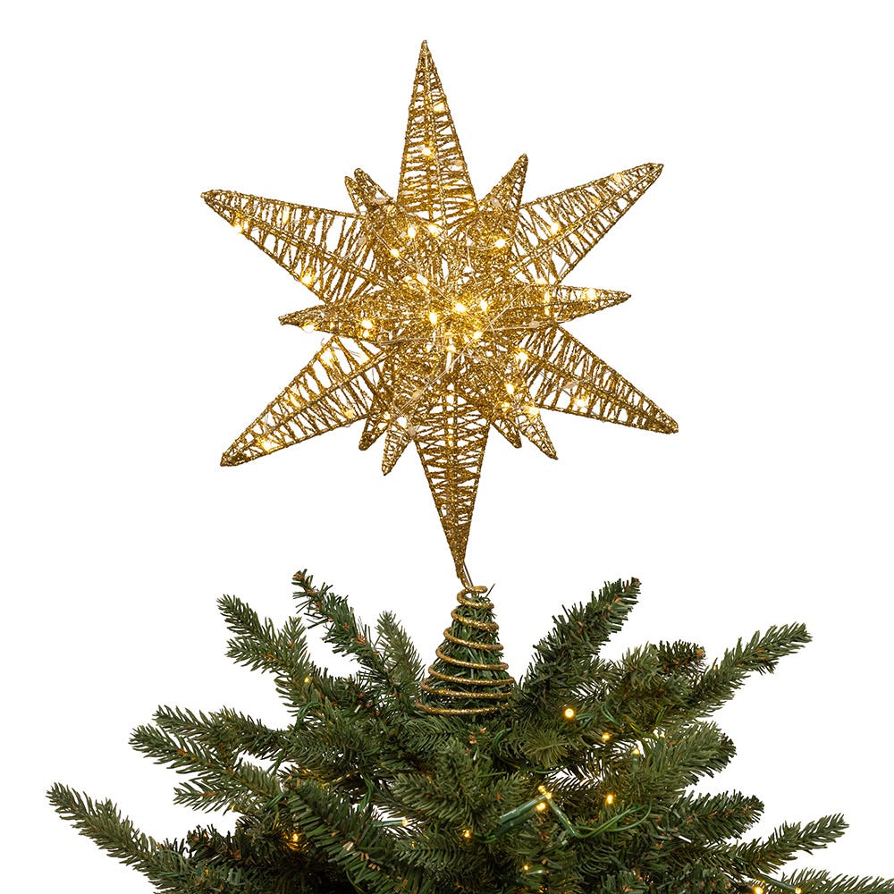 Gold star-shaped Christmas tree topper on a decorated tree with lights.