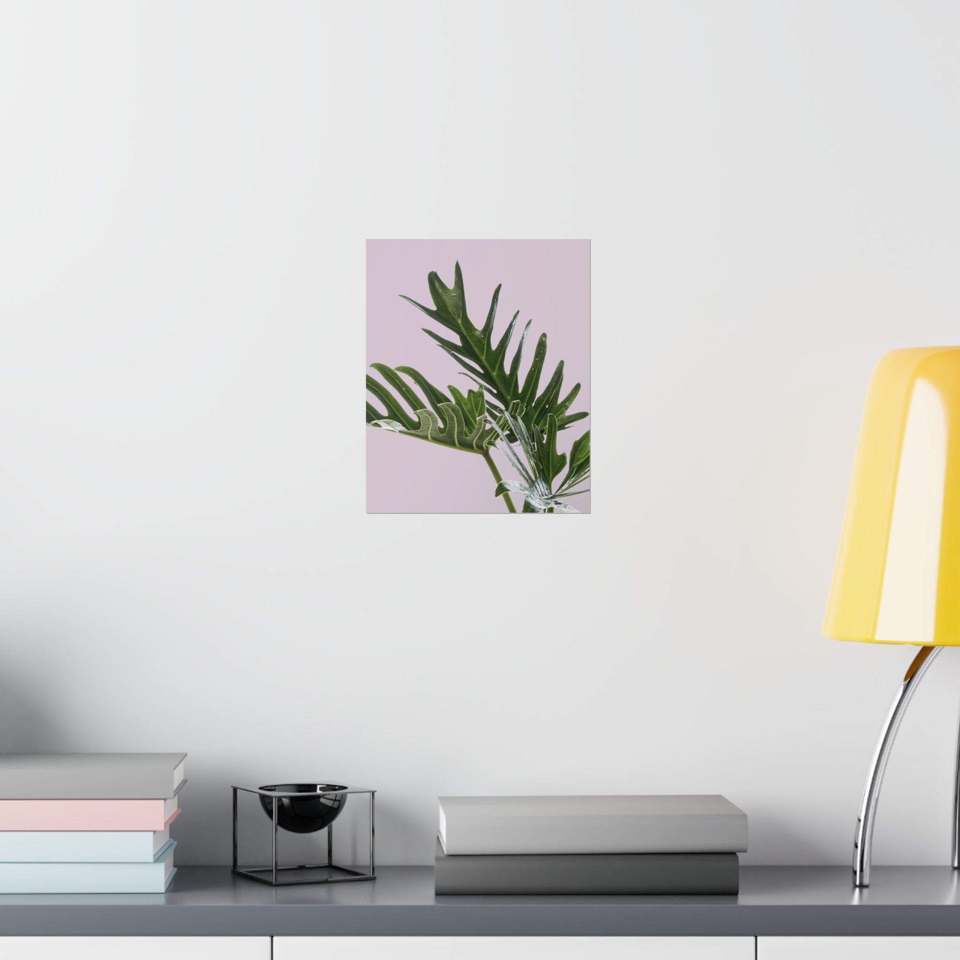 Framed plant picture on a wall above a desk with books and a lamp.