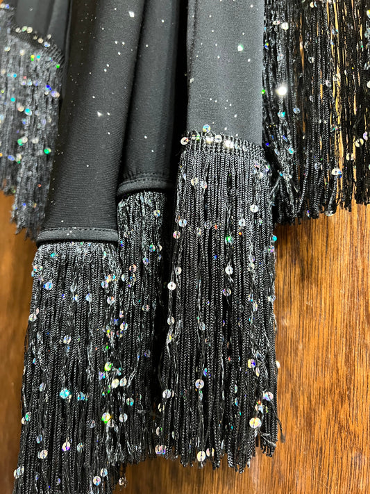 Black sequin dress with fringe details on a wooden surface