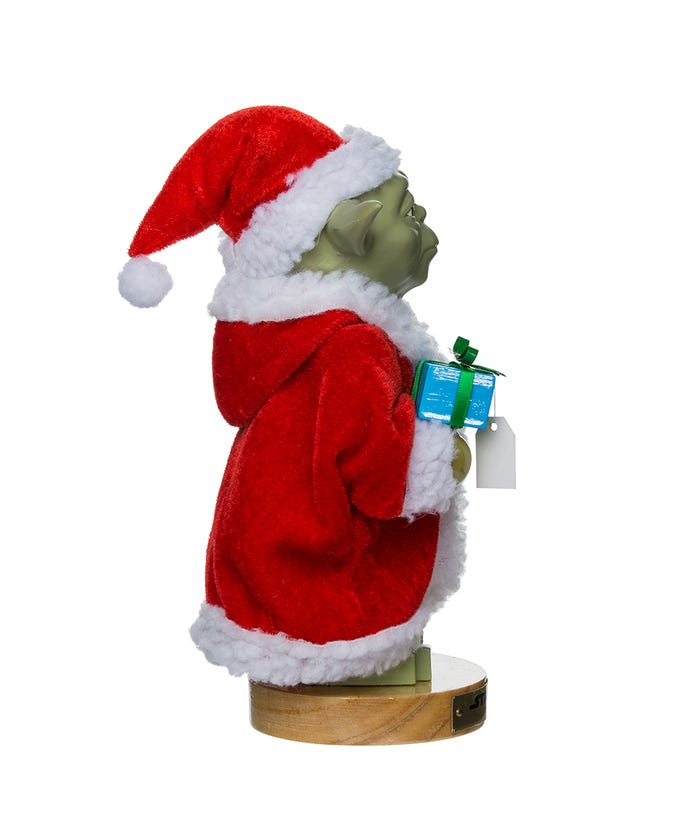 Green character in a red Santa outfit holding a gift on a white background