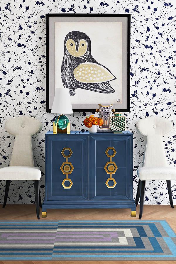 Blue cabinet with gold accents in a room with owl artwork and patterned wallpaper.