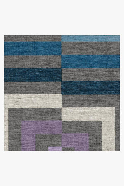 Geometric patterned rug with blue, gray, and purple squares on a white background