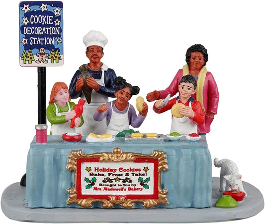 Decorative figurine of a cookie decoration station with people around a table.