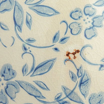 Close-up of a ceramic tile with blue floral pattern on a beige background