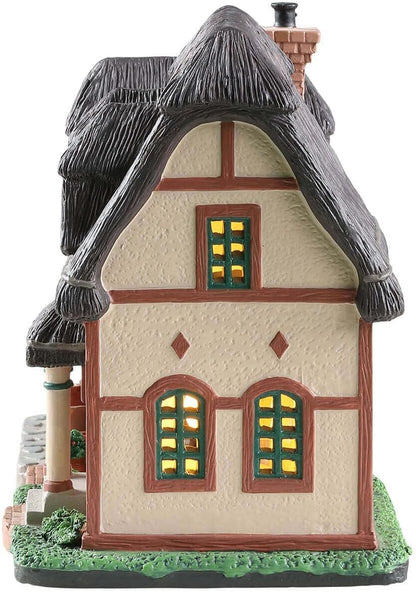 Decorative model of a thatched-roof house with lit windows on a white background