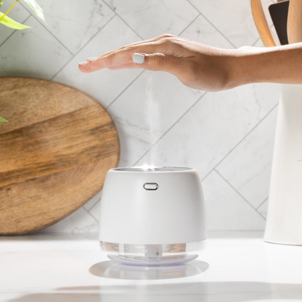 White humidifier on a white surface with a wooden cutting board in the background