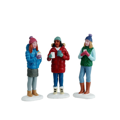 Three figurines of people in winter clothing on a white background