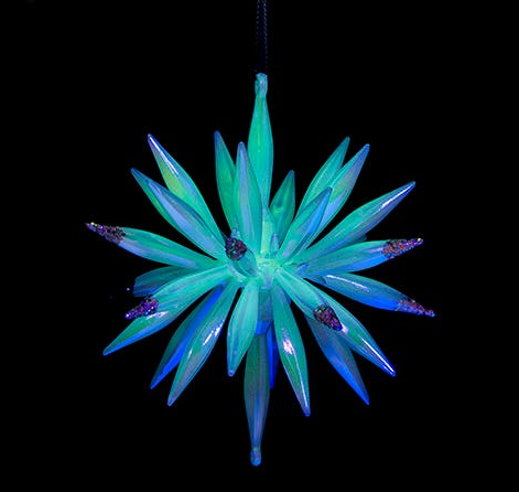 Decorative star-shaped ornament with green and blue spikes on a black background