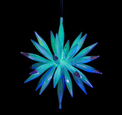 Decorative star-shaped ornament with green and blue spikes on a black background