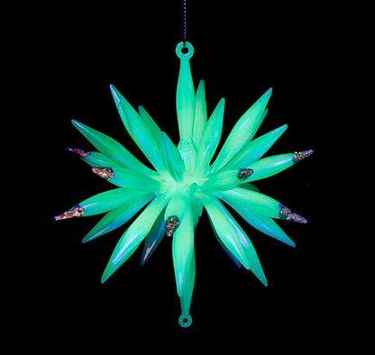 Green star-shaped ornament with small decorative elements on a black background